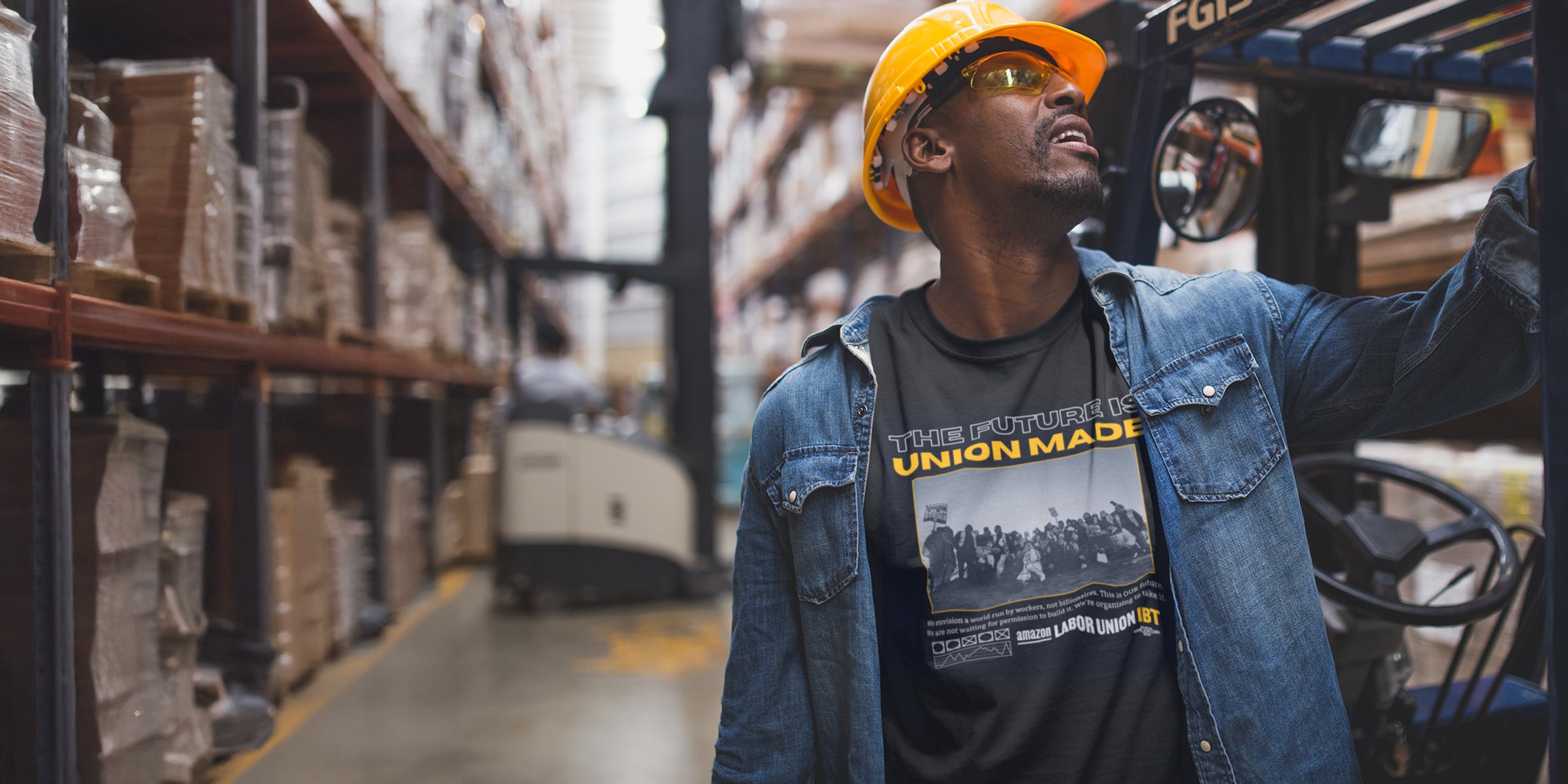 Person wearing a hard hat and denim jacket in a warehouse setting